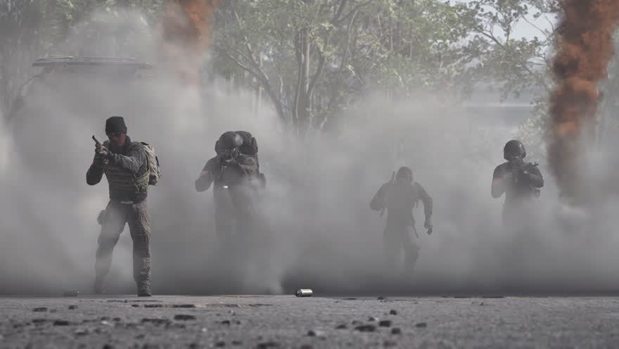 Vier Soldaten rücken durch dichten Staub und Rauch vor, nur als Silhouetten erkennbar.